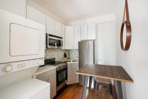 une cuisine avec des placards blancs et une table en bois dans l'établissement 24-4 New Private Terrace W D Apt Prime Gramercy, à New York