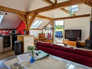 a living room with a couch and a tv at Romantic Barn, Private Hot-Tub near Diddly Squat 2 or 3 night stays in Chipping Norton