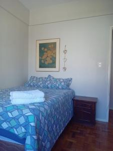 a bed with a blue comforter in a bedroom at Apto central completo perto de tudo in Caxias do Sul