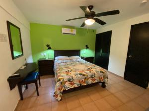 a bedroom with a bed with a ceiling fan and a desk at Hotel Marcianito in Isla Mujeres