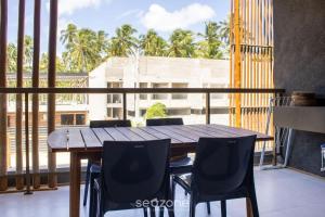 y balcón con mesa y sillas de madera. en TMH - Condomínio Essence em Porto de Pedras/AL, en Porto de Pedras