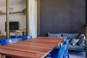 comedor con mesa de madera y sillas azules en TMH - Condomínio Essence em Porto de Pedras/AL, en Porto de Pedras