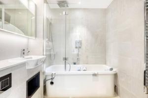 a white bathroom with a tub and a sink at Deluxe 2 Bed by Buckingham Palace in London
