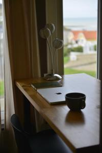 a desk with a laptop and a flower vase on it at La Perle Marine superbe vue mer terrasse 30m2 in Criel-sur-Mer