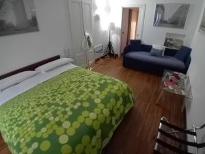 Room Inn في ميلانو: غرفة نوم بسرير اخضر واريكة زرقاء