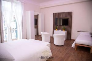 a white bedroom with a bed and two white chairs at La Regina Luxury Holiday Home in Cava deʼ Tirreni