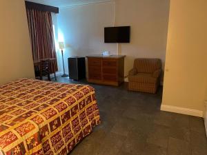 a hotel room with a bed and a chair and a television at Grand Inn in Fullerton