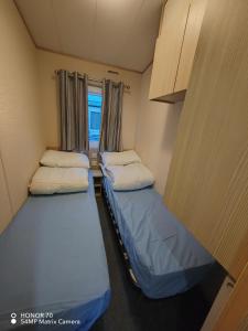 two beds in a small room with a window at Ocean Edge Holiday Park in Heysham