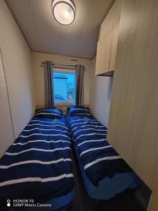 two beds in a small room with a window at Ocean Edge Holiday Park in Heysham