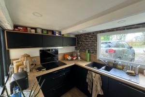 a kitchen with a sink and a window with a car outside at Norman house with jacuzzi in Touques