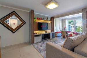 a living room with a couch and a television at Ao lado da Catedral - @stayhousetemporada in Canela