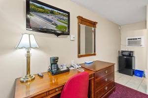 a desk with a red chair and a television on a wall at Nights Inn Owen Sound in Owen Sound