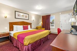 Habitación de hotel con cama y escritorio en Nights Inn Owen Sound, en Owen Sound