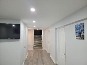 a hallway with white walls and a television and a staircase at Cozy Room in a Quiet Neighbourhood in Toronto