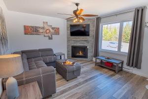 een woonkamer met een bank en een open haard bij Cottage Quebec - Olivine in Petite-Rivière-Saint-François