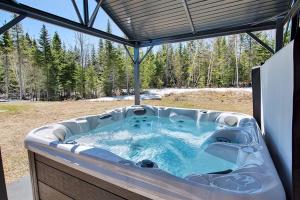 a hot tub in the backyard of a house at Cottage Quebec - Olivine in Petite-Rivière-Saint-François +3 photos
