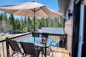 a patio with a table and an umbrella on a balcony at Cottage Quebec - Olivine in Petite-Rivière-Saint-François