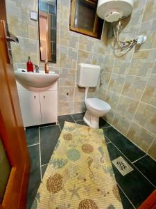 La salle de bains est pourvue de toilettes, d'un lavabo et d'un tapis. dans l'établissement Babér Apartmanház Balatonakarattya, à Balatonkenese