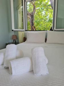 1 cama con toallas blancas y ventana en Filiatra Cosy House, en Filiatra