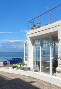 um edifício com uma mesa e bancos em frente ao oceano em Vitaminas - Casa de Playa y Café em Punta del Este