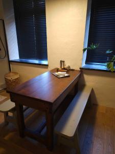 een houten tafel en bank in een kamer met 2 ramen bij Erfgoedlogies Fort Liezele 