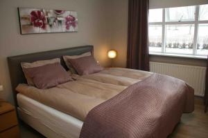 una camera da letto con un grande letto con cuscini rosa di Asa´s comfortable, cozy nest in the north. ad Akureyri