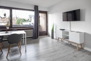 a white living room with a table and a tv at Biebrach's Ferienwohnungen in Wilhelmshaven