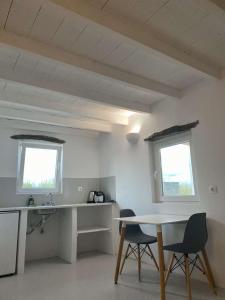 uma cozinha com duas janelas e uma mesa e cadeiras em Louloudas rooms paros em Molos Parou