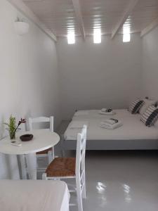 um quarto branco com uma cama, uma mesa e cadeiras em Louloudas rooms paros em Molos Parou