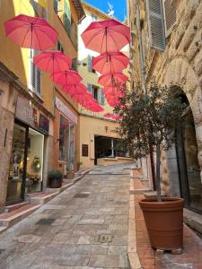 um beco com guarda-chuvas vermelhos pendurados sobre uma rua em L'AIR DU TEMPS, Superbe appartement, au coeur du Centre Historique de Grasse em Grasse