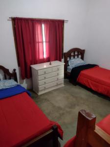 a bedroom with two beds and a dresser and a window at Ruedas Negras Casa de Campo in Los Árboles