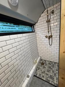 ein Bad mit einer Dusche und weißen Fliesen in der Unterkunft TERMINUSBUS in Crèvecoeur-le-Grand