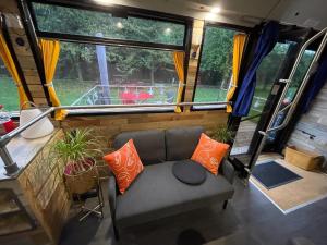 ein Wohnzimmer in einem Wohnwagen mit Sofa und Kissen in der Unterkunft TERMINUSBUS in Crèvecoeur-le-Grand