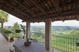 een patio met een tafel en stoelen op een balkon bij Sky & Vineyards - Melograno - in La Morra