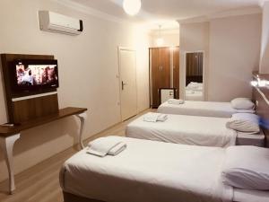 AkcaabatにあるLarok Hotelのベッド3台、薄型テレビが備わるホテルルームです。