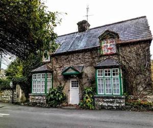 a stone house with green windows and a white door at Carraig Ban in Cong