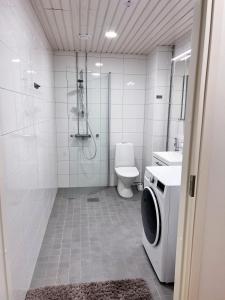 a bathroom with a shower toilet and a washing machine at Upouusi luksusasunto! / Areena / Juna-asema /4hlö in Tampere