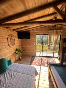 um quarto com uma cama e uma grande janela em Cardinal Glamping em Guatapé