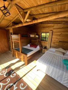 a bedroom with two bunk beds in a log cabin at Cardinal Glamping in Guatapé