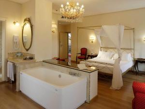 ein großes Bad mit einer Badewanne und einem Bett in der Unterkunft Giotto Hotel & Spa in Assisi