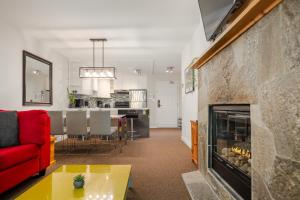 a living room with a red couch and a fireplace at Steps to the Ski Hill with Rooftop Hot Tub by Harmony Whistler in Whistler