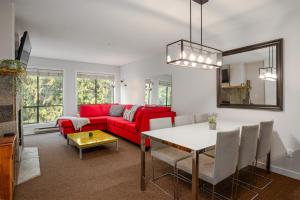 a living room with a red couch and a table at Steps to the Ski Hill with Rooftop Hot Tub by Harmony Whistler in Whistler
