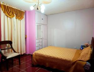 - une chambre avec un lit et une chaise dans l'établissement Amplio y cómodo departamento con garage, à Puyo