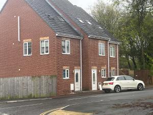 un coche blanco estacionado frente a una casa de ladrillo en COSY 3 - City View en Sunderland