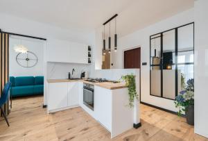 a kitchen with white cabinets and a blue couch at Apartament Gospody 23 in Gdańsk