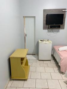 Cette chambre comprend une télévision, une table et un lit. dans l'établissement Pousada Capim Dourado Jalapão São Felix TO, à São Félix do Tocantins