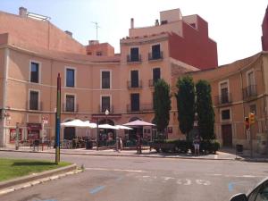 a building with tables and umbrellas on a city street at CASA RO in Tarragona