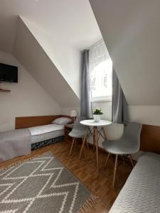 a attic room with two beds and a table at Pensjonat Melodia in Pobierowo