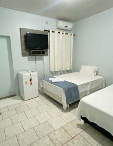 a room with two beds and a flat screen tv at Pousada Capim Dourado Jalapão São Felix TO in São Félix do Tocantins