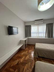 a hotel room with two beds and a flat screen tv at Columbia Palace Hotel in Buenos Aires